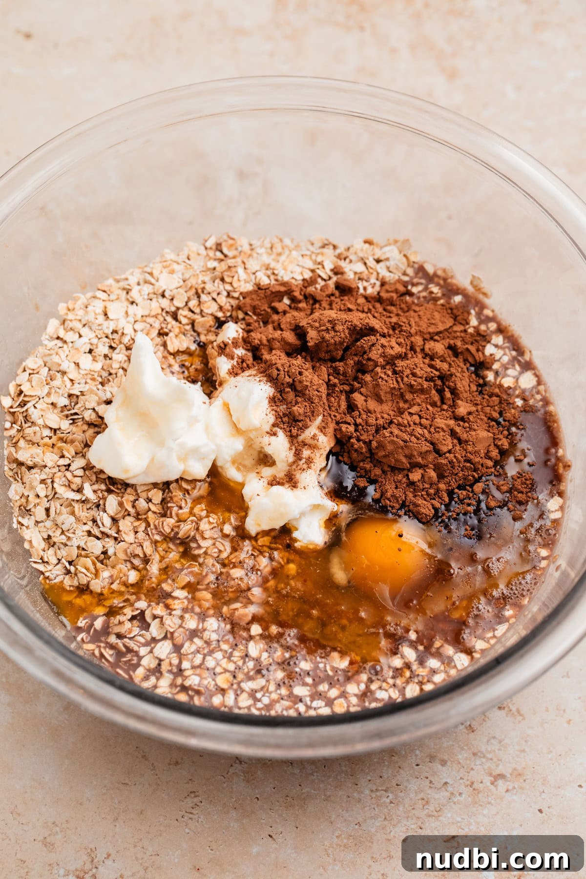 Decadent Chocolate Baked Oats Recipe for Breakfast and Snacks 5 Oats, cocoa powder, eggs, butter and other ingredients in bowl before mixing.