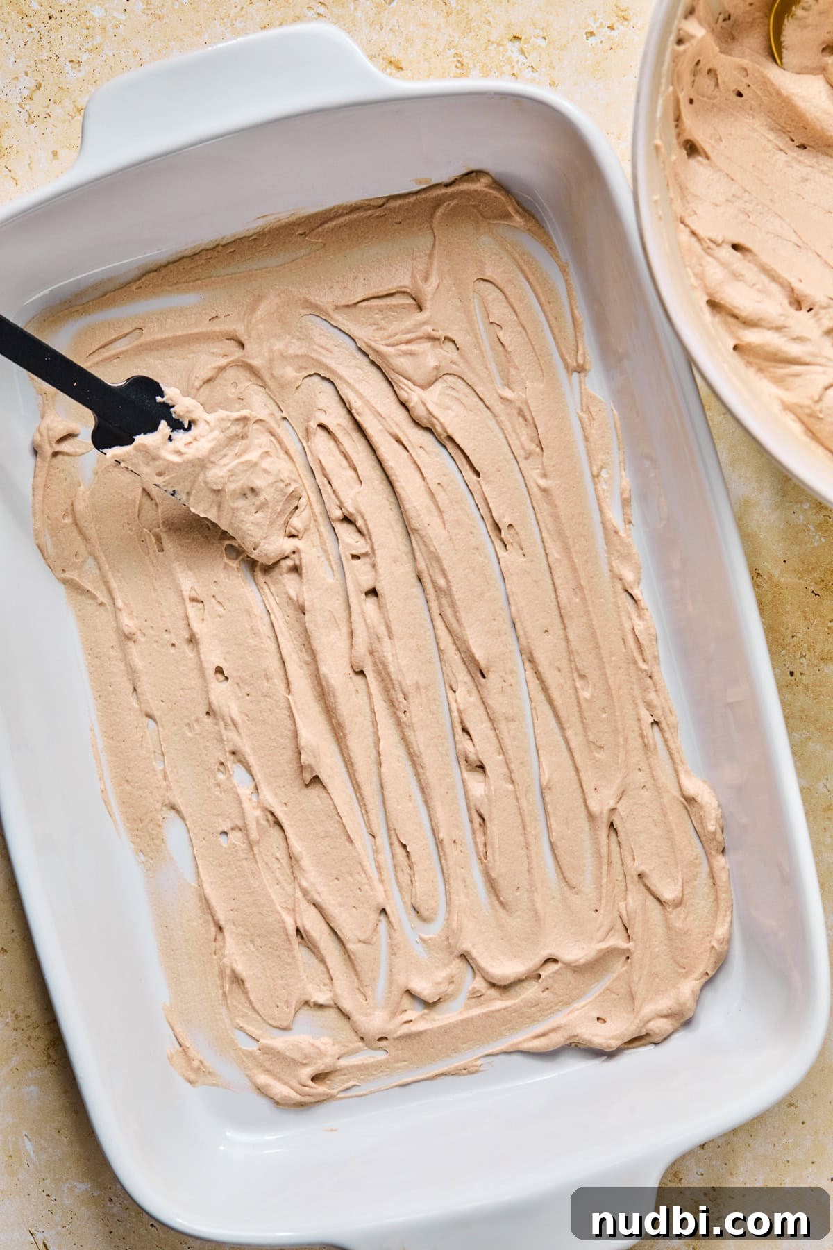 Decadent No-Bake Chocolate Icebox Cake Recipe 11 Chocolate whipped cream mixture spread in layer in pan with spatula.