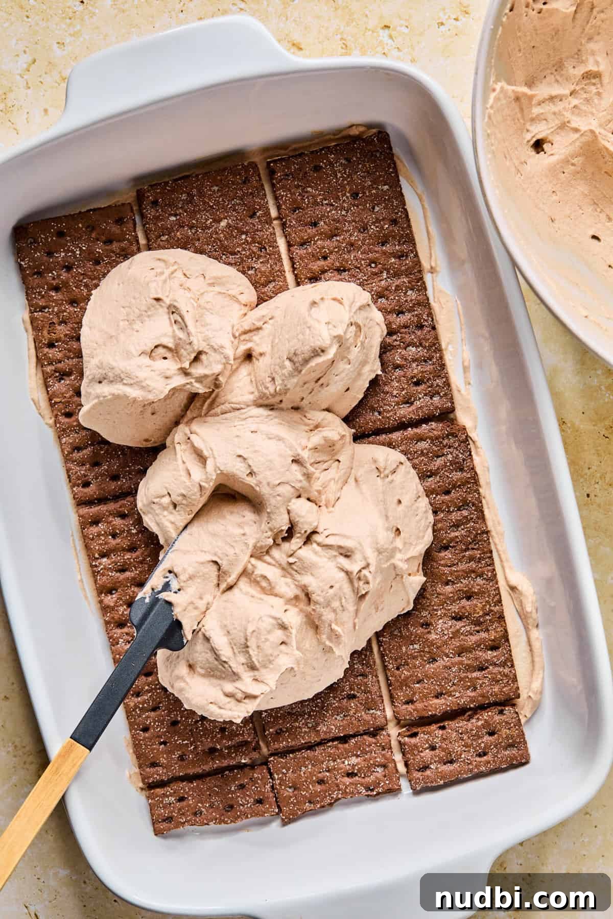 Decadent No-Bake Chocolate Icebox Cake Recipe 13 Dollops of chocolate cream mixture over top of chocolate graham layer for icebox cake.