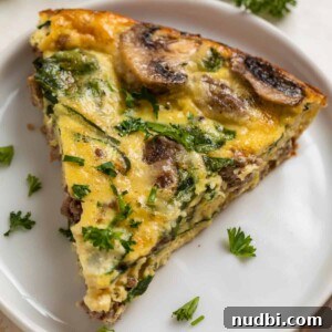 Crustless mushroom quiche with beef, swiss and spinach on white plate and topped with chopped parsley and chives.