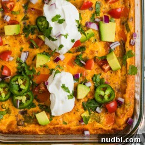 Chorizo egg bake in glass baking pan topped with sour cream, jalapeño, avocado, etc.