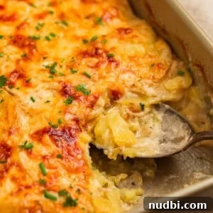 Gruyere scalloped potatoes in pan with serving spoon.