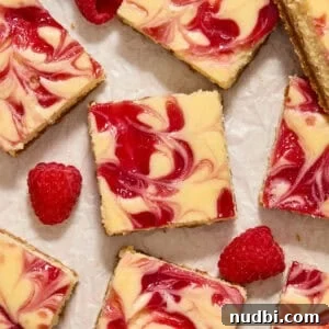 Raspberry swirl white chocolate cheesecake bars arranged on surface with fresh raspberries.