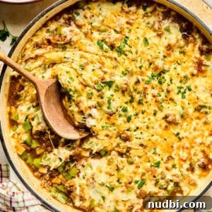 Philly Cheesesteak Rice Bowl Recipe — Savory Steak & Peppers 18 Cheese topped Philly cheesesteak skillet mixture in pan with wood spoon.