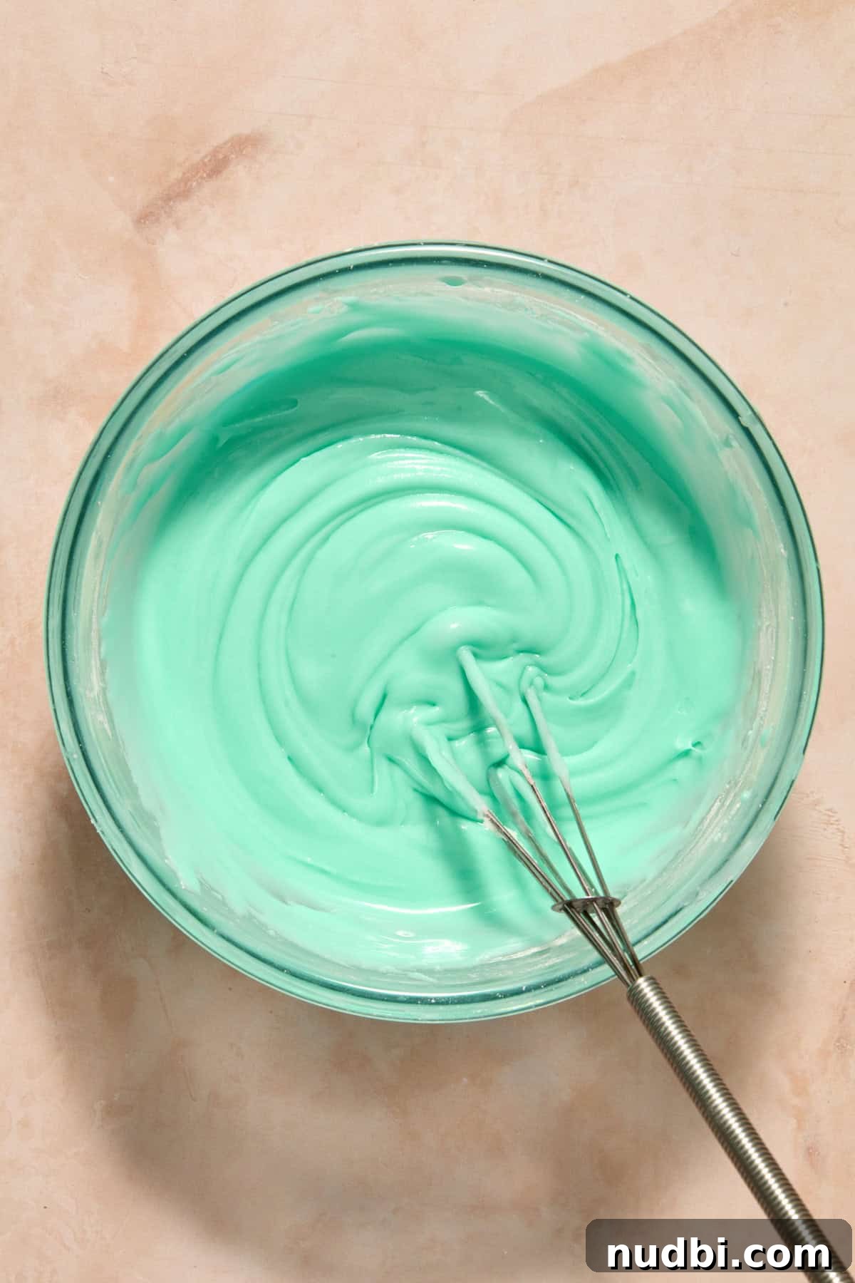 Speckled Easter Egg Shortbread Cookies Recipe 12 Turquoise icing with whisk in bowl.