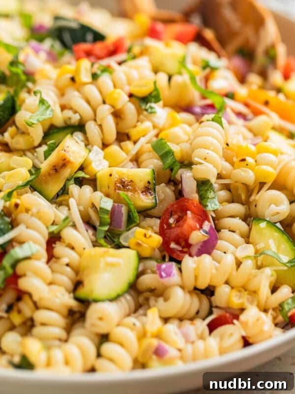 Italian Grinder Pasta Salad Recipe for Perfect Picnic Meals 14 Zucchini pasta salad in serving bowl with wood spoon.
