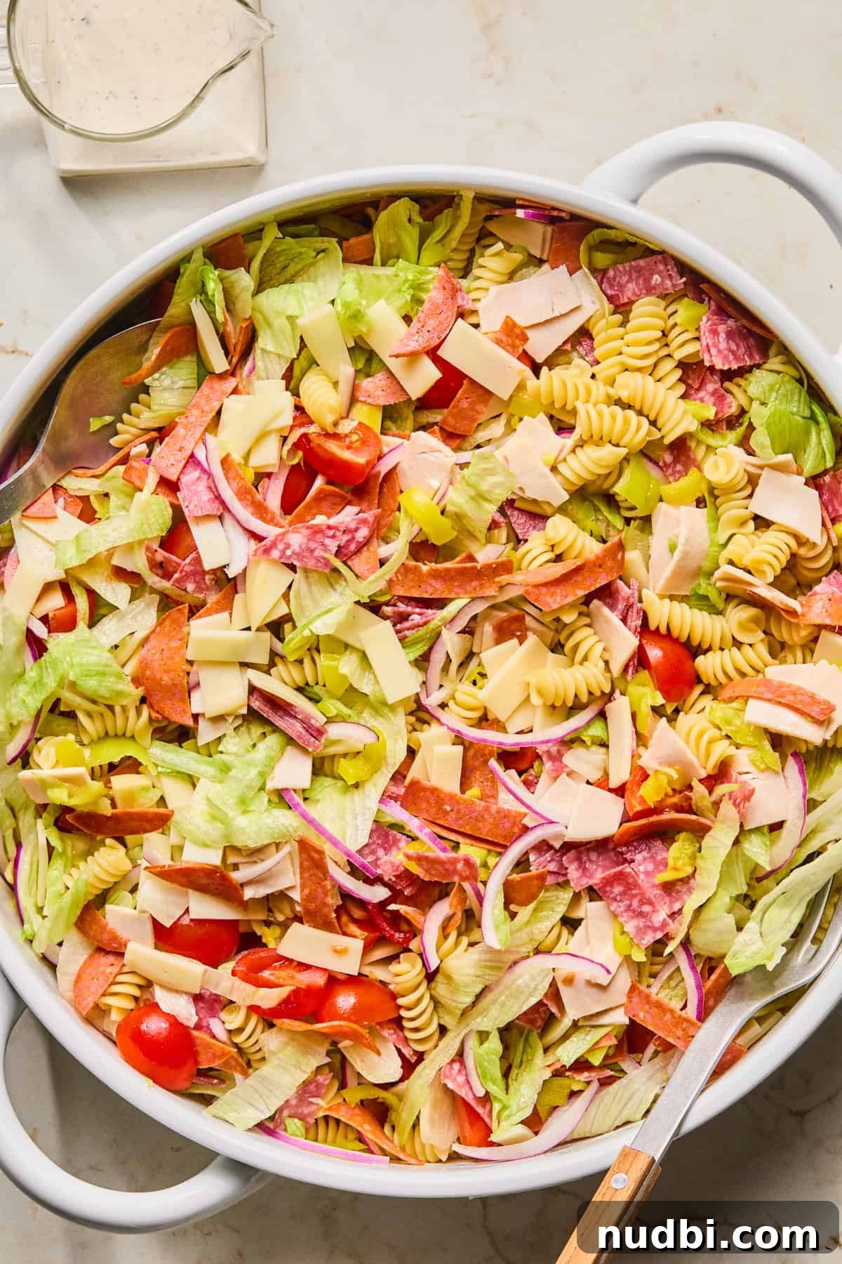 Italian Grinder Pasta Salad Recipe for Perfect Picnic Meals 6 Grinder pasta salad ingredients in bowl tossed before adding dressing.