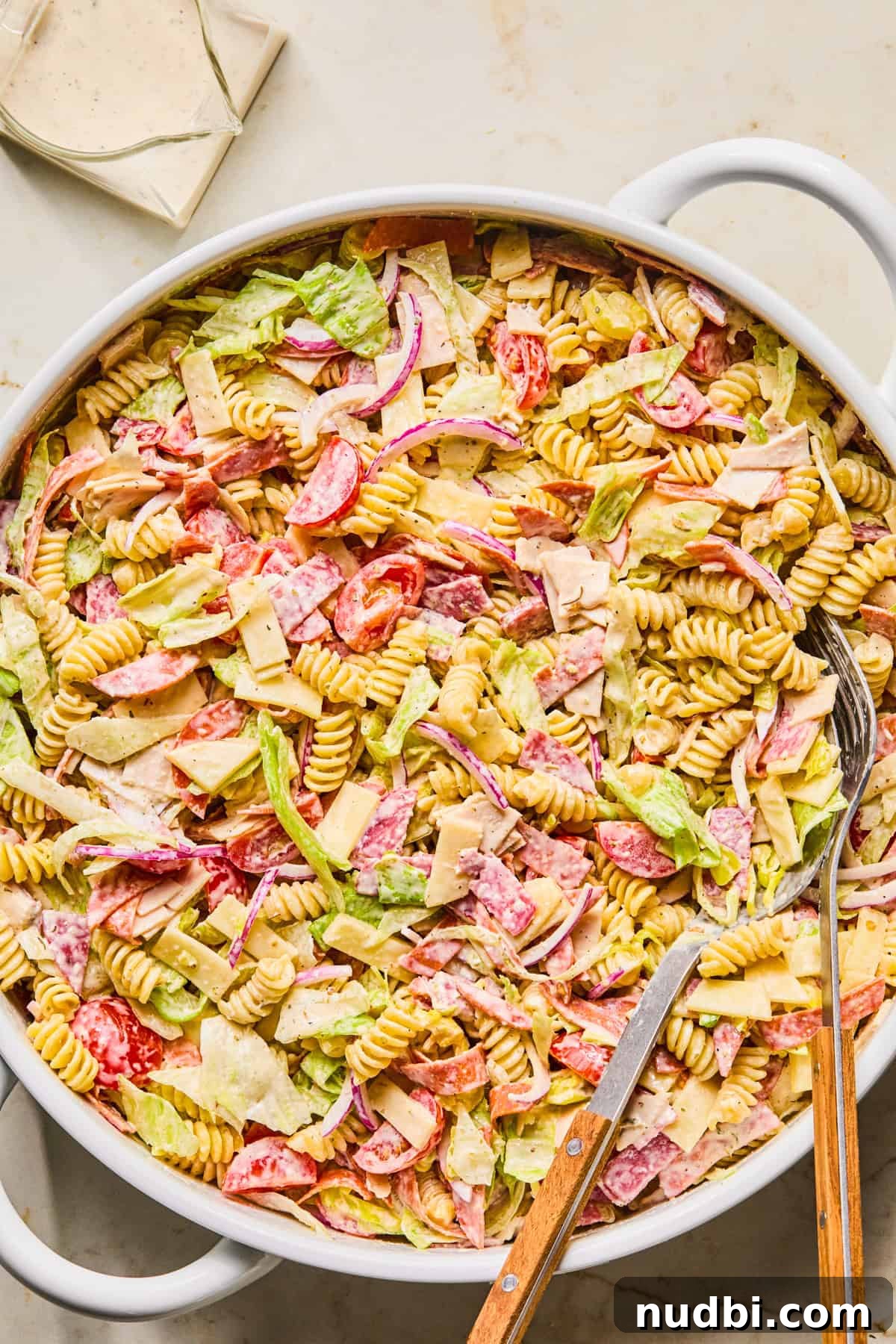 Italian Grinder Pasta Salad Recipe for Perfect Picnic Meals 10 Tossed pasta salad in bowl with turkey, provolone, salami, lettuce and other ingredients.