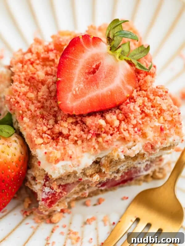 No-Bake Funfetti Cheesecake Recipe for Celebrations 13 Layered strawberry icebox cake topped with strawberry crunch on plate with fresh strawberry garnish.