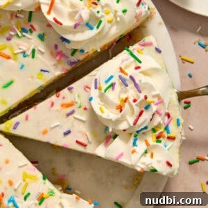 No-Bake Funfetti Cheesecake Recipe for Celebrations 15 Slice of no-bake funfetti cheesecake with piped whipped cream and rainbow sprinkles on top.