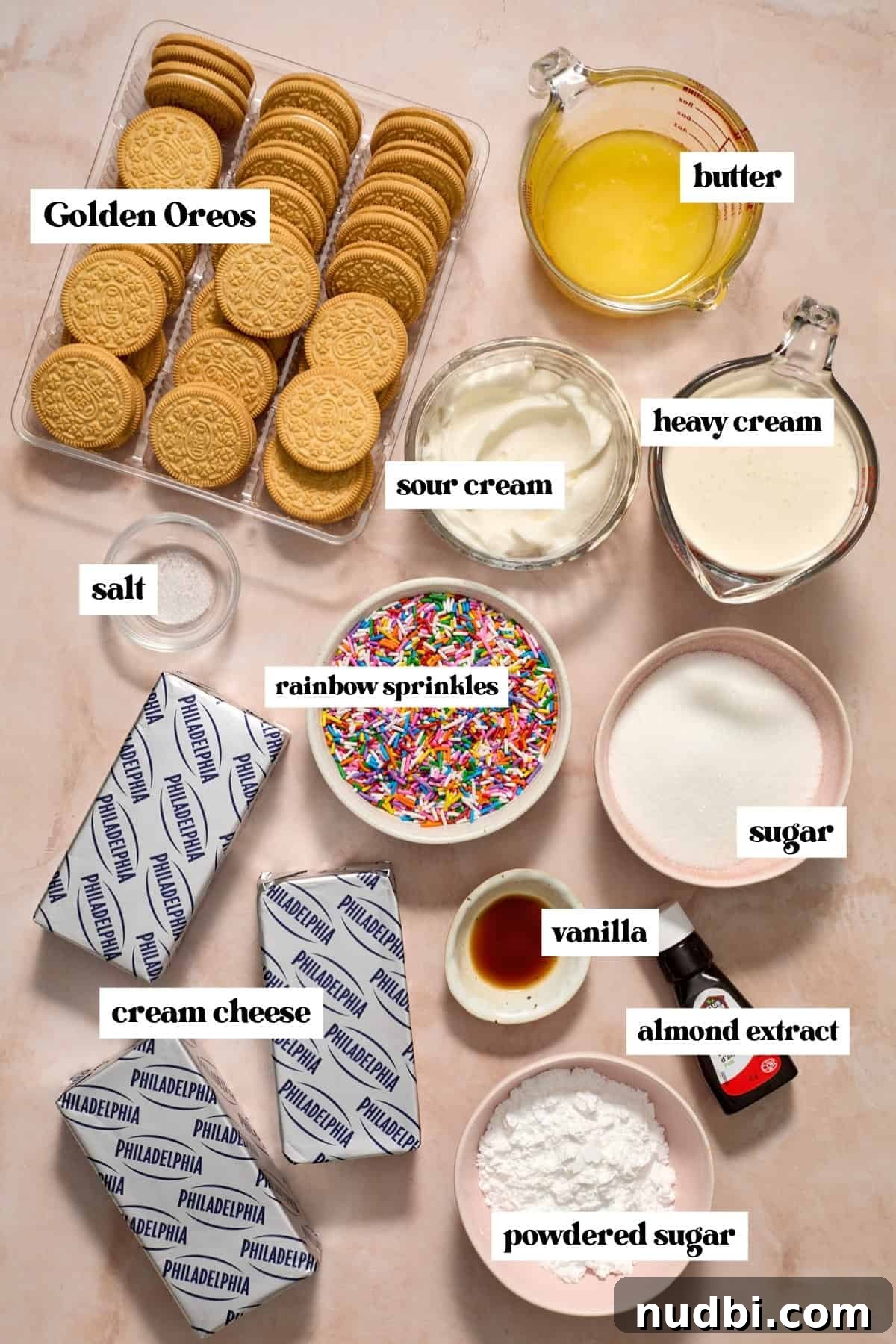 No-Bake Funfetti Cheesecake Recipe for Celebrations 4 Golden oreos, cream cheese, butter, and other labeled ingredients on surface.