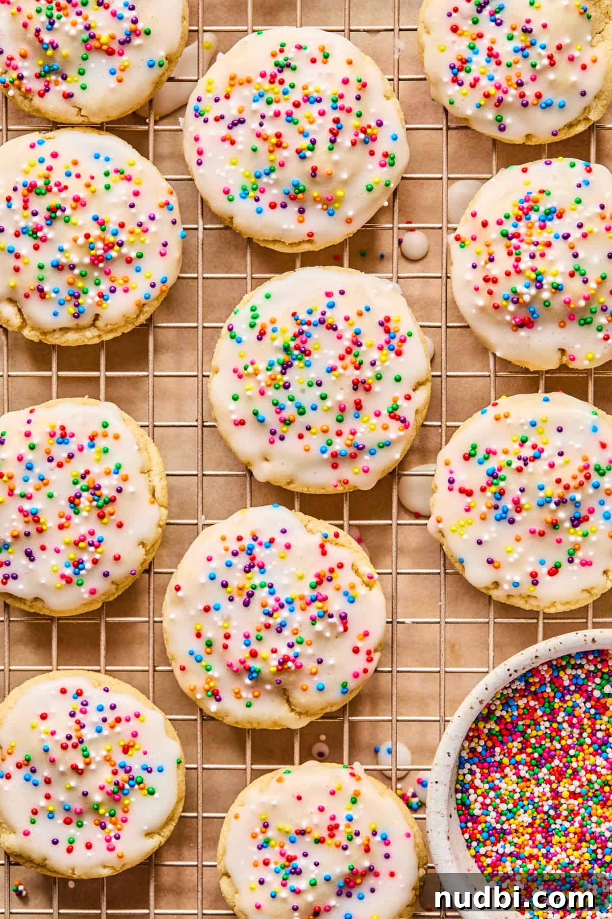 Iced Sugar Cookie Recipe: Soft, Chewy Cookies with Royal Icing 2 Iced sugar cookies with nonpareils sprinkles on wire rack.