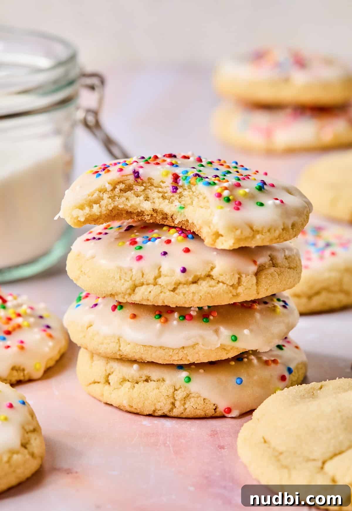 Iced Sugar Cookie Recipe: Soft, Chewy Cookies with Royal Icing 13 Stack of iced sugar cookies with bite taken out of top cookie.