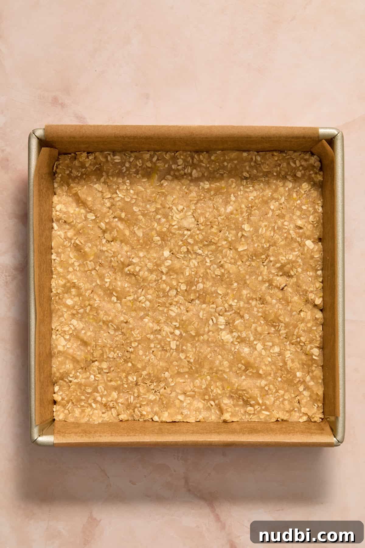 Lemon oat bar mixture pressed into lined pan.