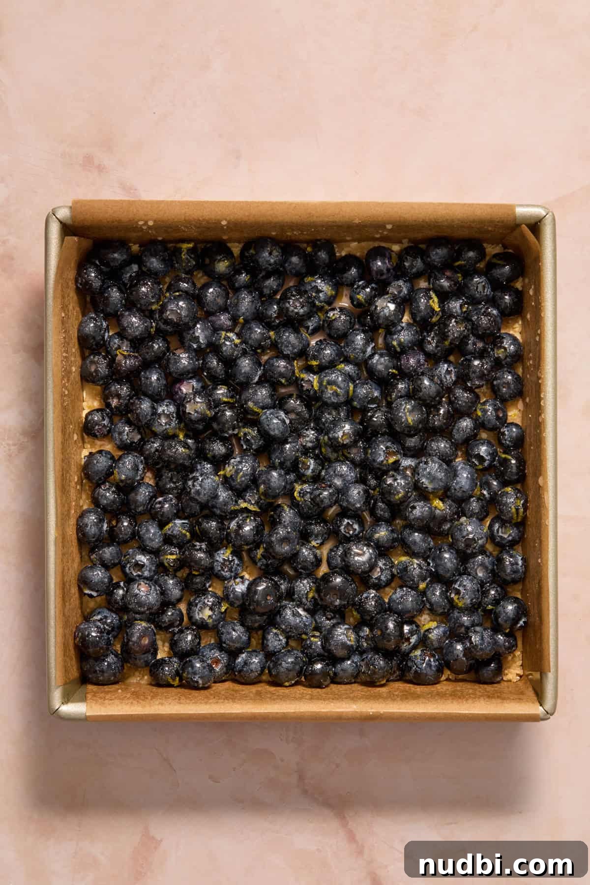 Blueberry lemon mixture added to pan with oat layer.