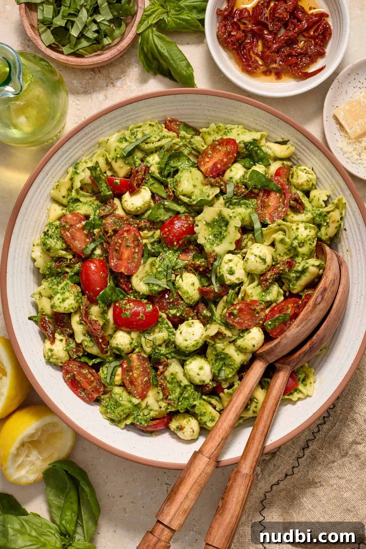 Creamy Tortellini Pesto Salad with Cherry Tomatoes & Spinach 2 Serving bowl with tortellini pesto salad and salad serving utensils.