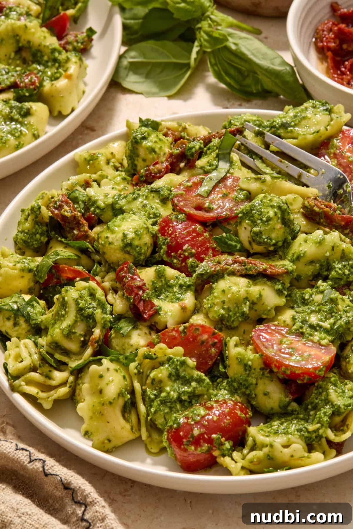 Creamy Tortellini Pesto Salad with Cherry Tomatoes & Spinach 11 Plate with tortellini pesto salad and fork propped on plate.