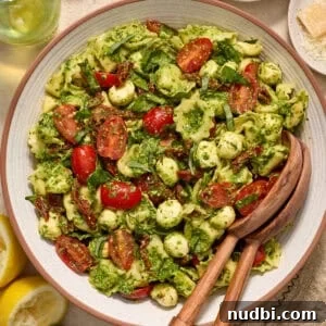 Creamy Tortellini Pesto Salad with Cherry Tomatoes & Spinach 12 Bowl with prepared pesto tortellini salad topped with fresh chopped basil.
