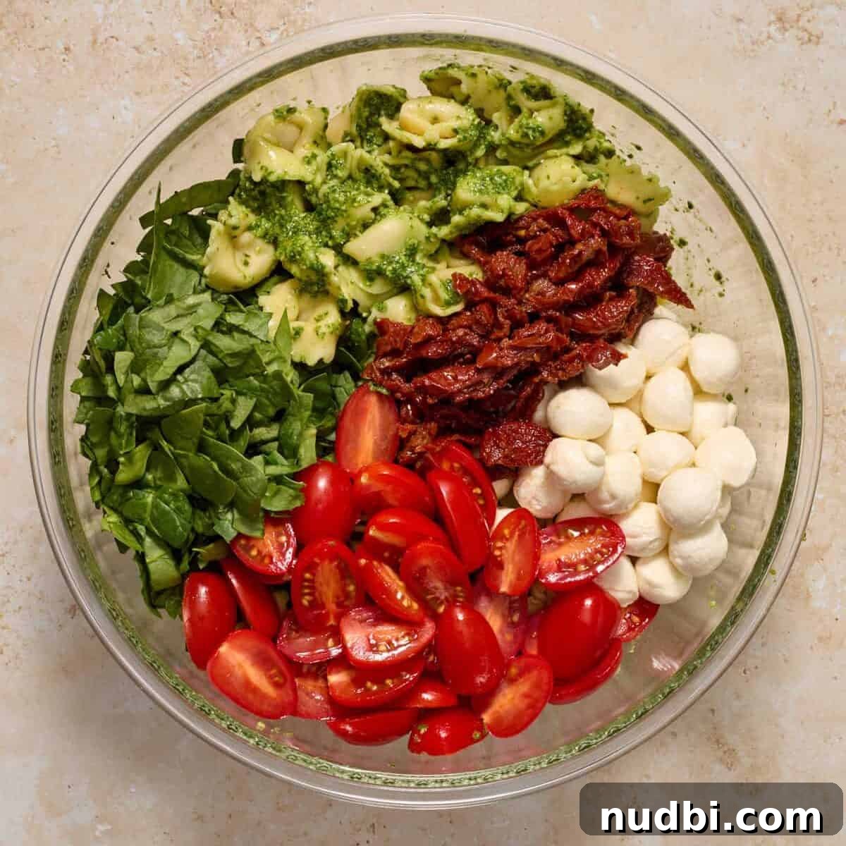 Creamy Tortellini Pesto Salad with Cherry Tomatoes & Spinach 9 Tomatoes, spinach, mozzarella and other ingredients added to bowl with tortellini.