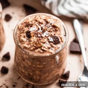 Triple Chocolate Overnight Oats Recipe for Chocolate Lovers 6 Chocolate overnight oatmeal in jar with spoon and chocolate pieces beside it.