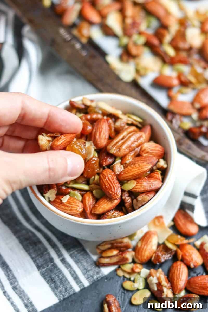 Maple Roasted Trail Mix Recipe with Nuts & Seeds 4 Hand holding cluster of easy trail mix with roasted almonds, pecans and other nuts.