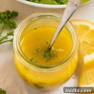 Lemon dijon dressing in glass jar with spoon.