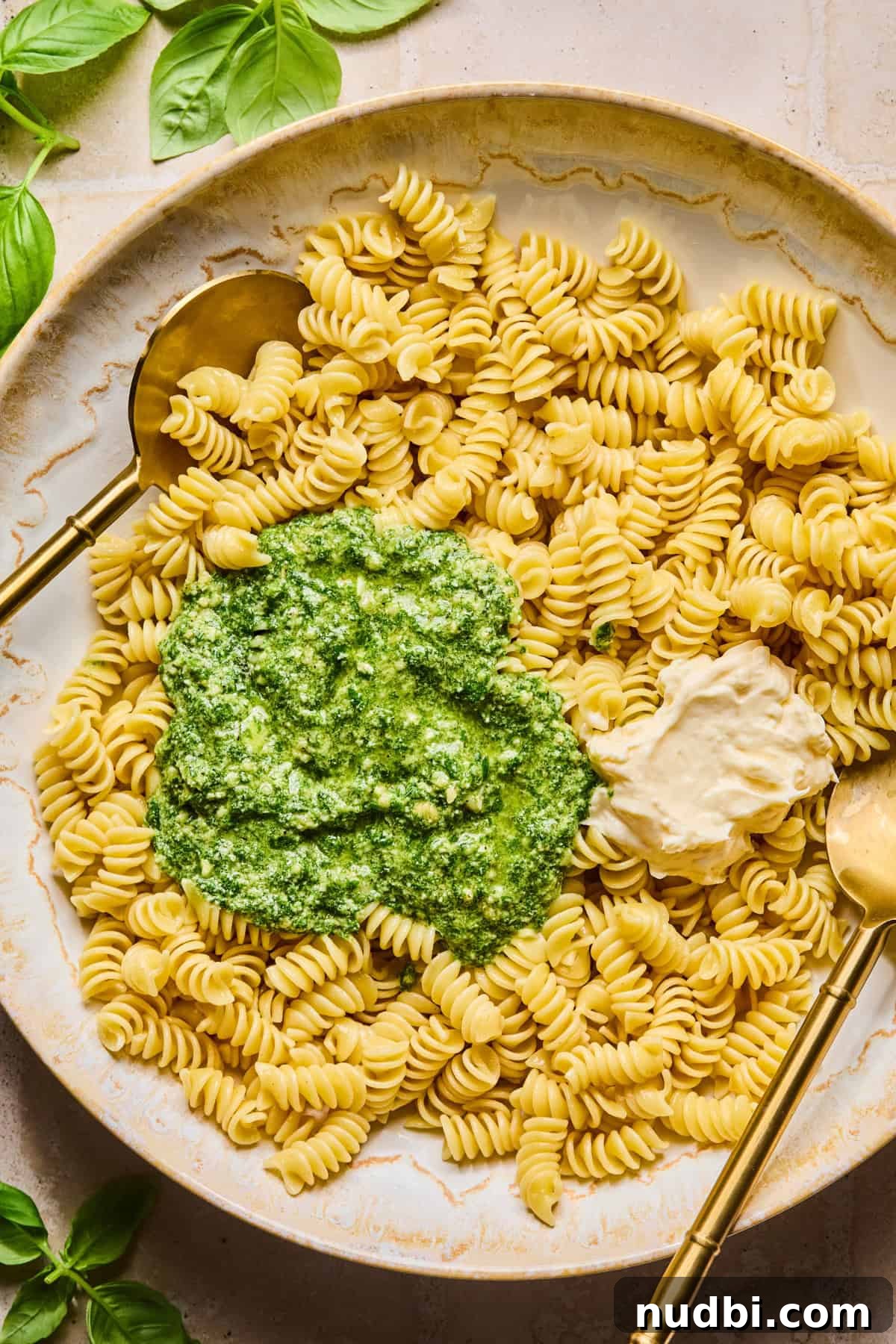 Pesto Chicken Pasta Salad with Sun-Dried Tomatoes and Basil 7 Pesto and mayo over top of pasta in bowl with spoons.