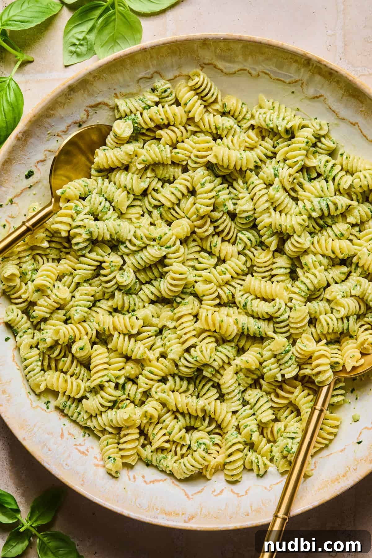 Pesto Chicken Pasta Salad with Sun-Dried Tomatoes and Basil 8 Pesto tossed with rotini pasta with utensils.