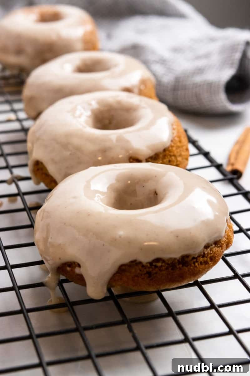 Apple Cider-Glazed Apple Cinnamon Donuts Recipe 7 Freshly glazed donuts on cooling rack.