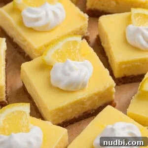 Creamy Lemon Bars with Graham Cracker Crust Recipe 14 Sliced creamy lemon bars topped with dollop of whipped cream and lemon slice.