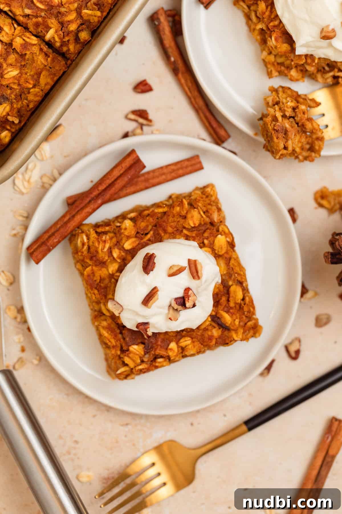 White dish with pumpkin baked oats with cinnamon sticks propped beside it.