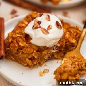 Slice of pumpkin oatmeal bake topped with yogurt and chopped pecans.