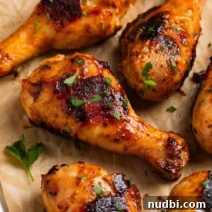 Sticky Honey Mustard Chicken Drumsticks Recipe 15 Honey mustard chicken drumsticks on parchment with chopped parsley.