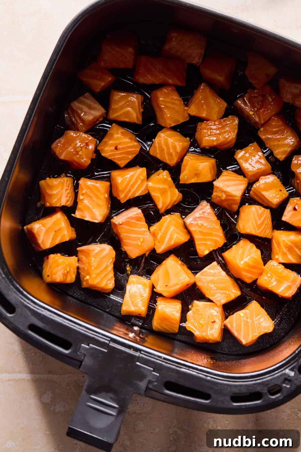 Teriyaki Salmon Rice Bowl with Scallions and Sesame 7 Air fryer with marinaded salmon bites before cooking.