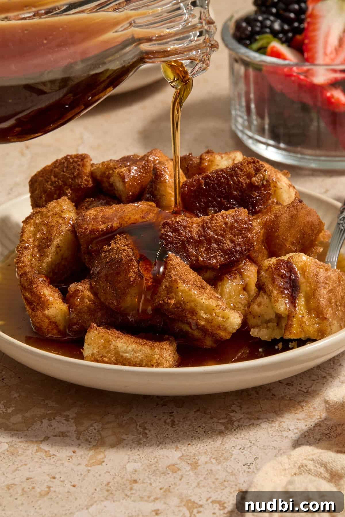 Overnight French Toast Casserole with Maple Cinnamon Glaze 2 Serving of Texas toast French toast bake on plate with maple being poured over it.