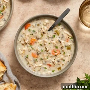 Slow-Cooker Chicken and Wild Rice Soup Recipe 11 Overhead view of creamy chicken wild rice soup in bowl topped with chopped parsley.