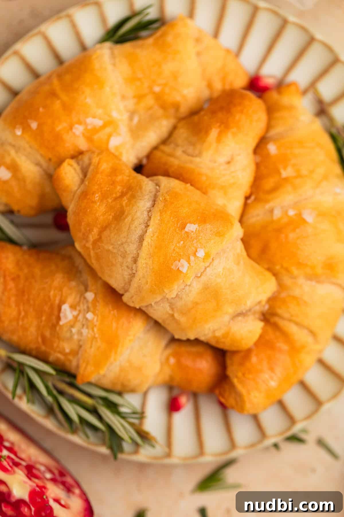 Baked Brie Crescent Rolls with Honey & Cranberry Jam 2 Pomegranate, brie and rosemary stuffed crescent rolls on plate.