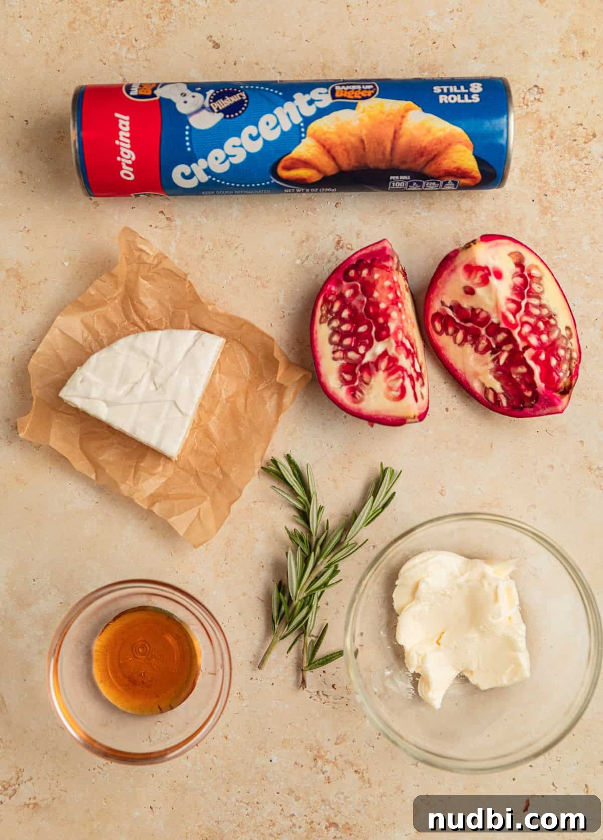 Baked Brie Crescent Rolls with Honey & Cranberry Jam 4 Crescent roll package, wedge of brie, rosemary sprigs and other ingredients on surface.