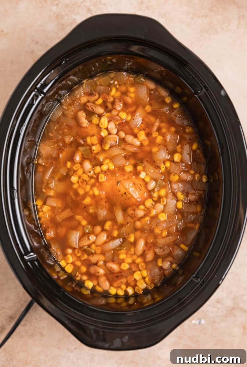 Creamy Slow Cooker White Chicken Chili Recipe 7 Cooked chicken chili in crockpot before chicken is shredded.