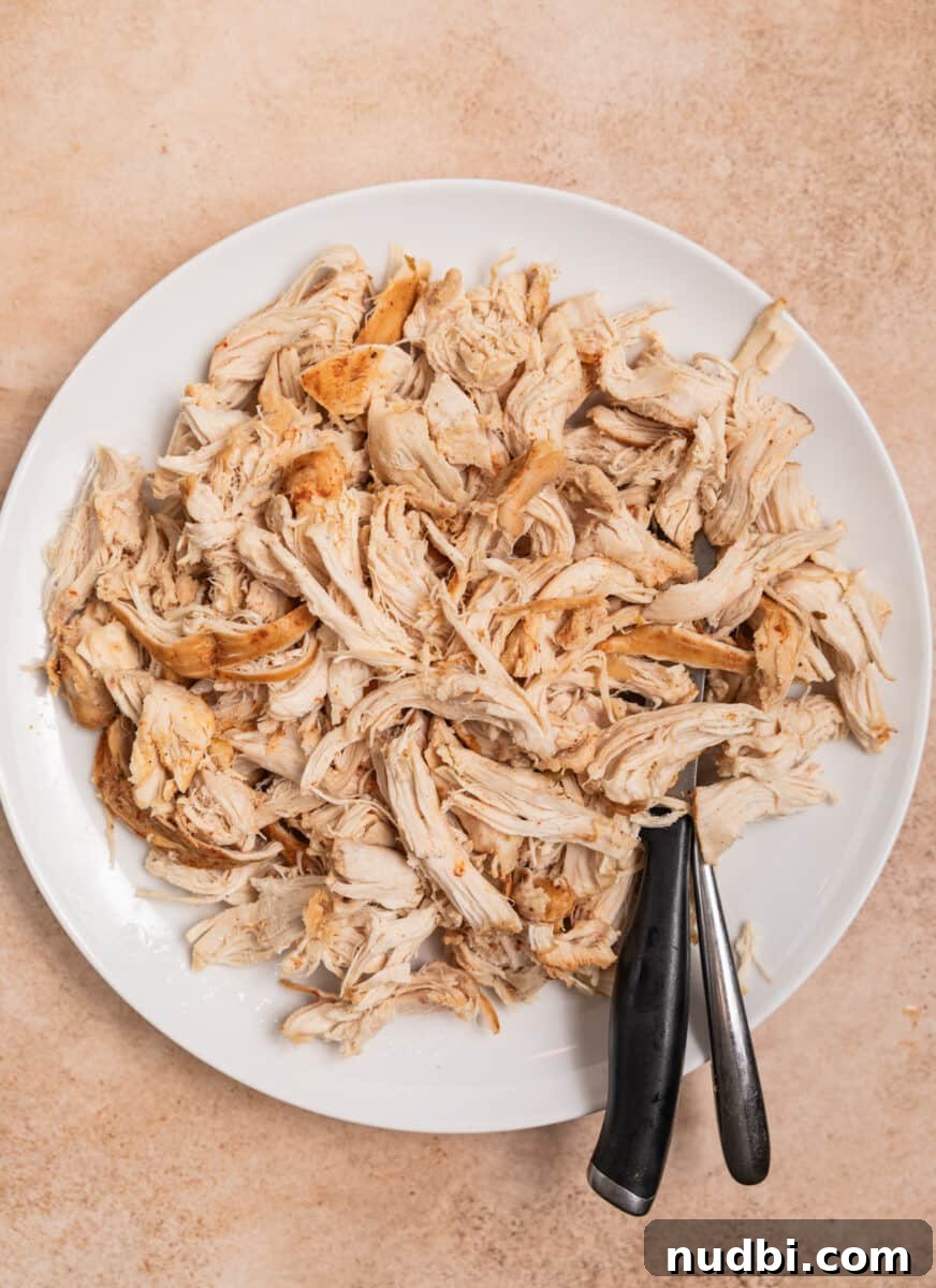 Creamy Slow Cooker White Chicken Chili Recipe 8 Chicken shredded on plate with knife and fork.
