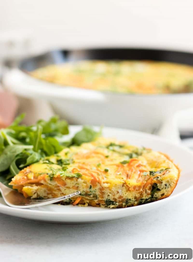 Spiralized Sweet Potato and Baby Arugula Frittata 2 Slice of sweet potato frittata with baby arugula on plate with fork.