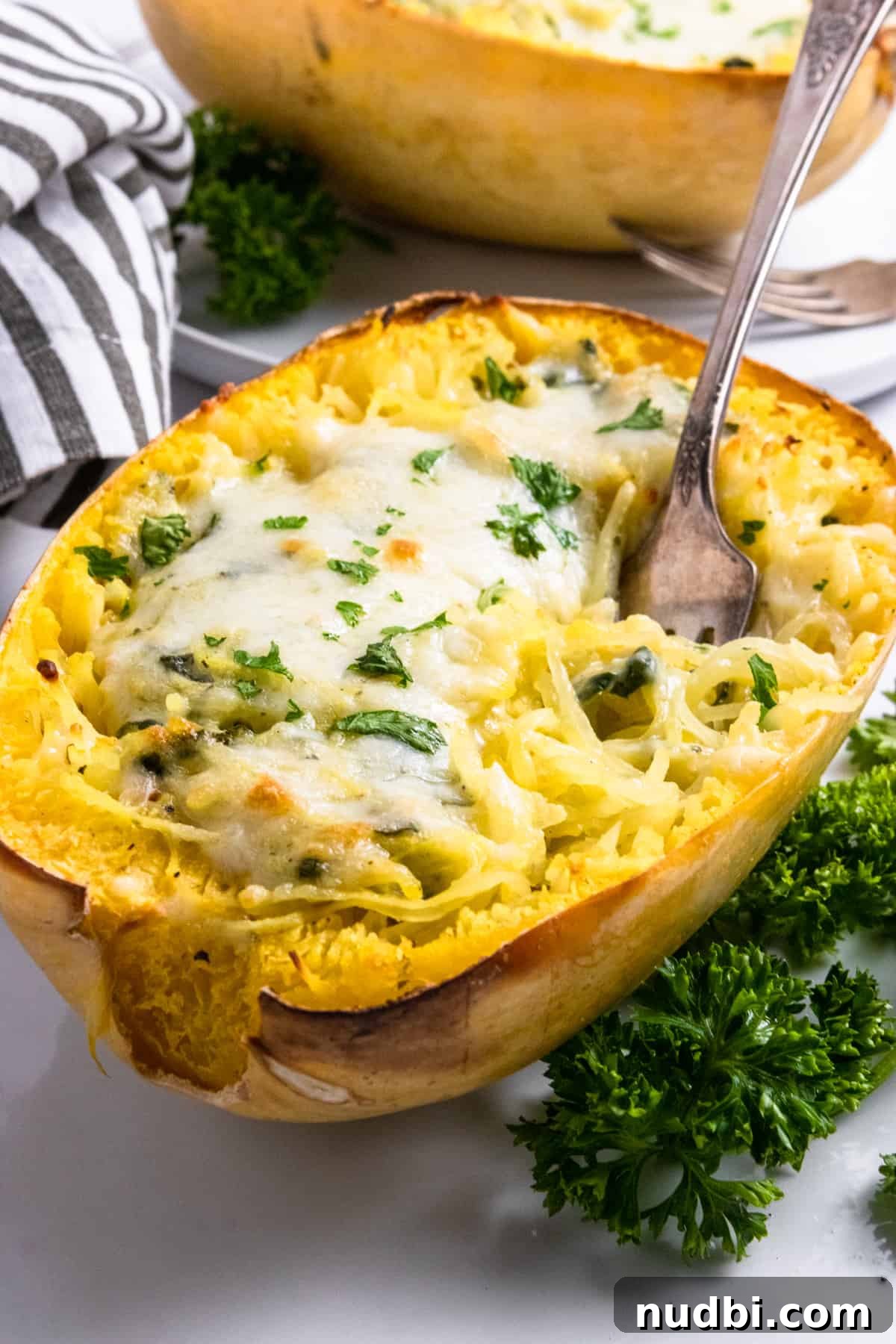 Spaghetti squash with cheese and pesto baked on top with spoon.