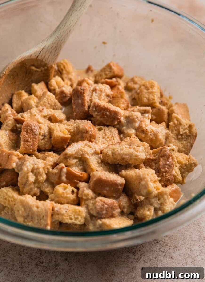 Cinnamon French Toast Muffins: Quick Breakfast Muffin Recipe 7 Brioche bread pieces mixed with French toast egg mixture in bowl with wooden spoon.