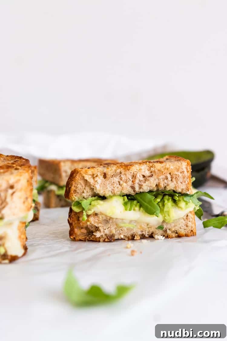 Havarti Grilled Cheese with Creamy Avocado & Baby Arugula 4 Half of a havarti grilled cheese with avocado and arugula.