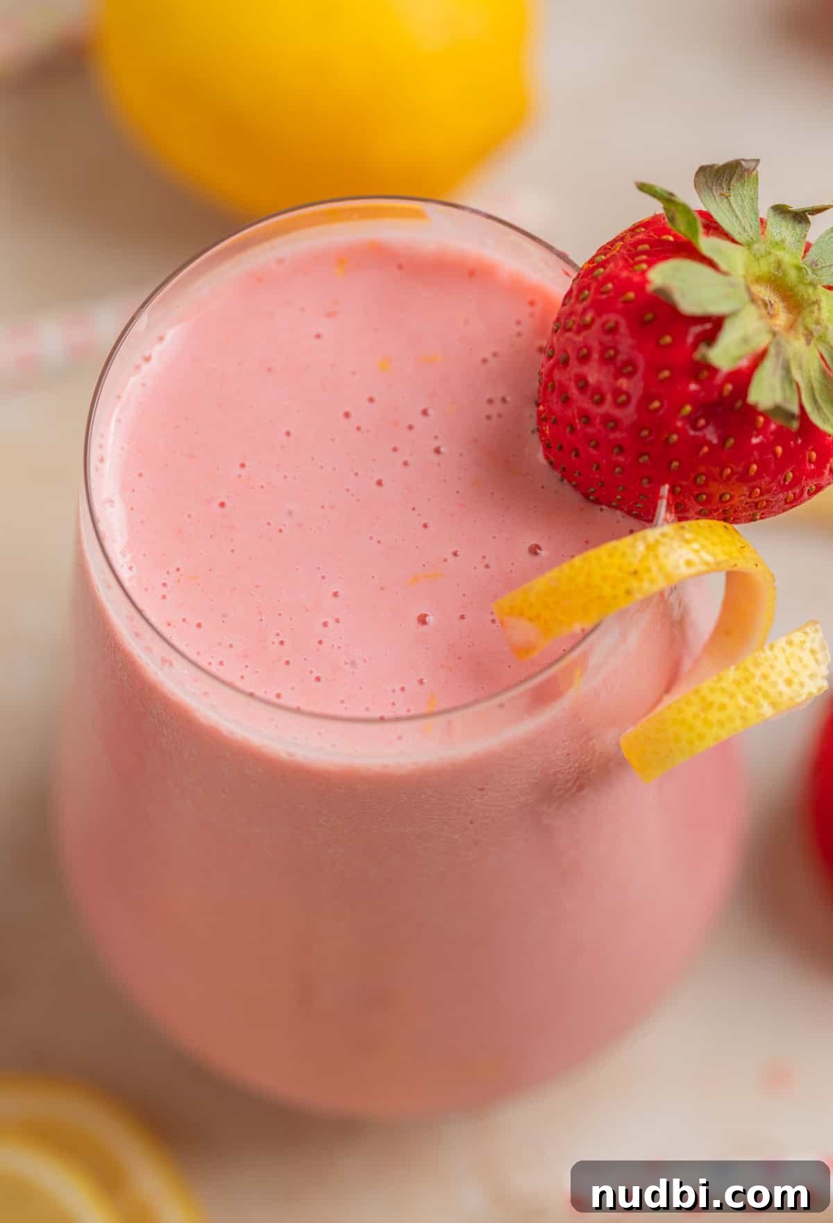 Refreshing Strawberry Lemonade Smoothie Recipe for Summer Sips 2 Strawberry lemonade smoothie in glass with lemon zest and strawberry garnish.