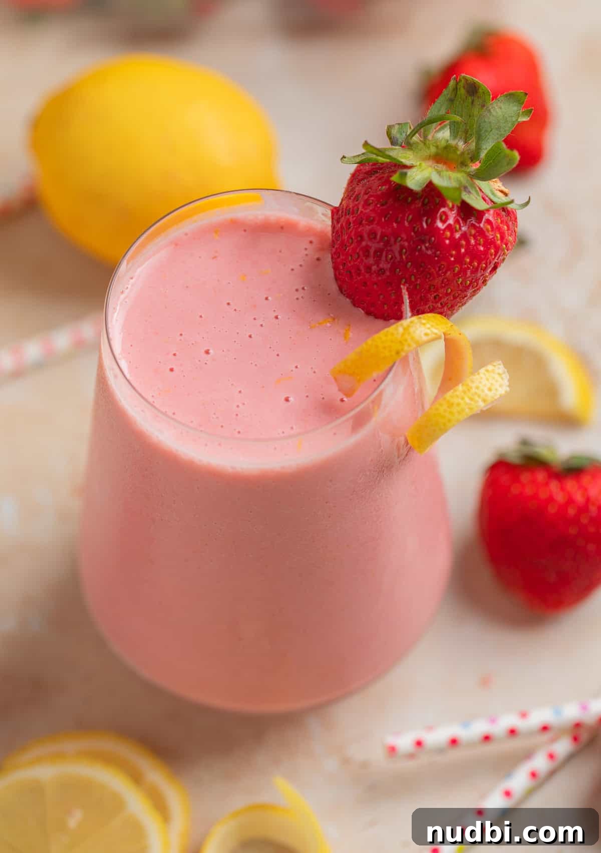 Refreshing Strawberry Lemonade Smoothie Recipe for Summer Sips 5 Smoothie in glass with lemon and strawberries and straws surrounding.
