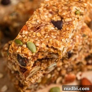 Homemade Trail Mix Bars Recipe – Portable Snack Bars for Hiking 12 No bake trail mix oat bars stacked on top of each other with bite taken out of top bar.