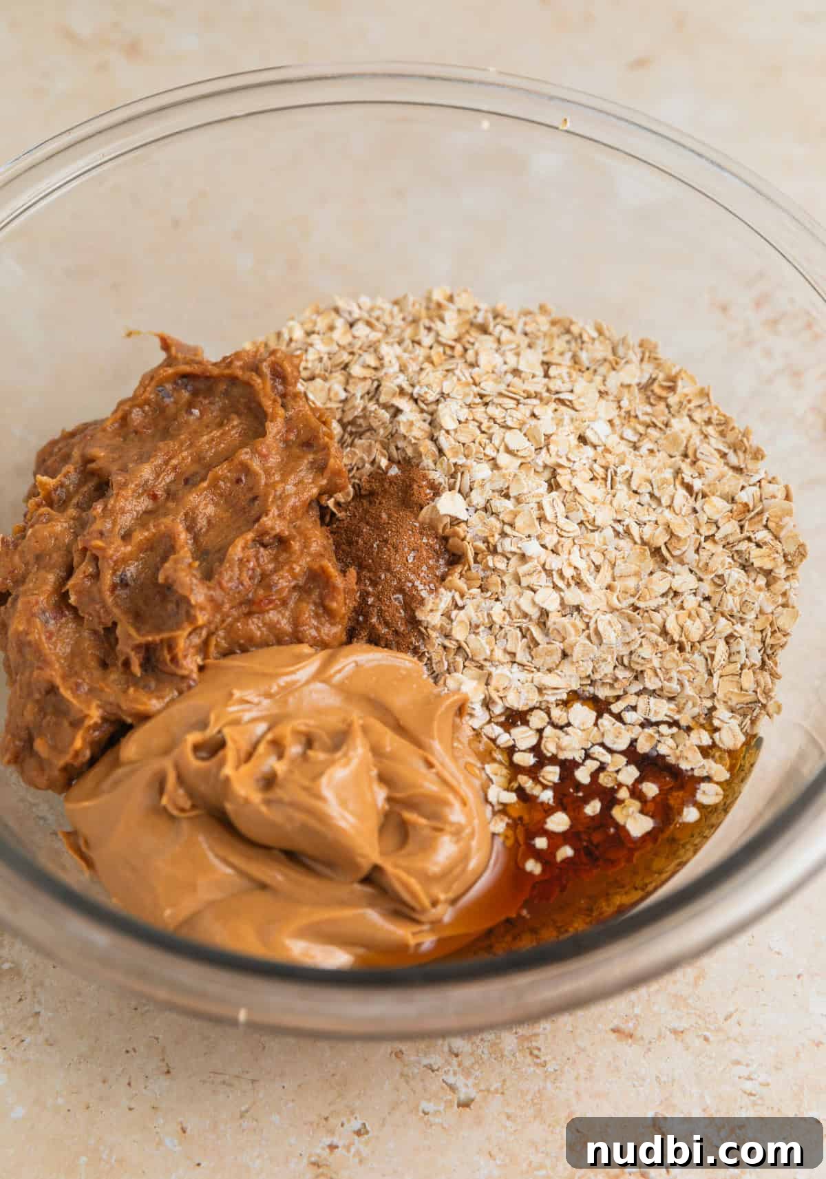 Homemade Trail Mix Bars Recipe – Portable Snack Bars for Hiking 6 Quick oats, peanut butter, date paste and maple syrup in glass bowl.