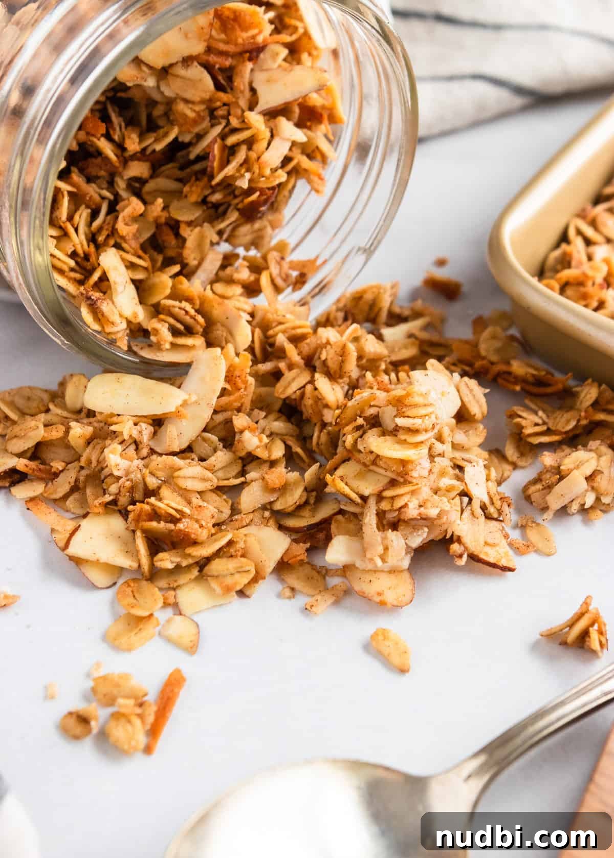 Crunchy Homemade Granola Recipe with Oats and Nuts 2 Jar of granola poured out next to baking sheet.