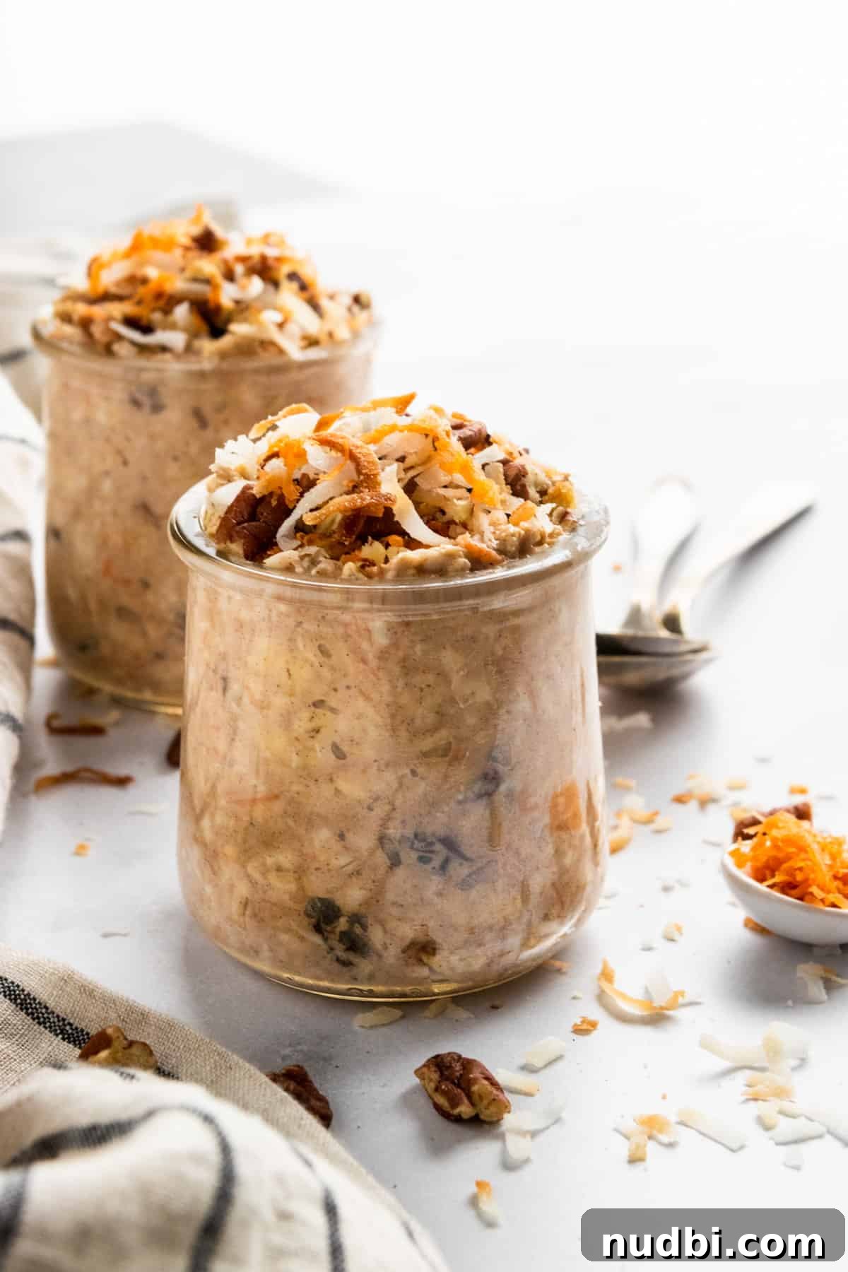 Carrot Cake Overnight Oats Recipe for Make-Ahead Breakfast 2 Overnight Oatmeal in jars with spoonful of shredded carrot.